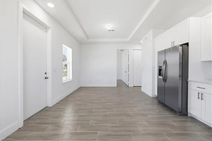 Open-concept area featuring wood-finish tile flooring, recessed lighting, and a tray ceiling
