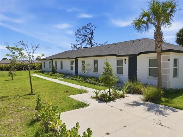 Contemporary duplex exterior featuring white stucco, dark gray shingle roof, and a palm tree