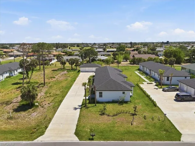 Aerial perspective showcasing multiple properties with dark shingle roofs, white exteriors, and concrete driveways