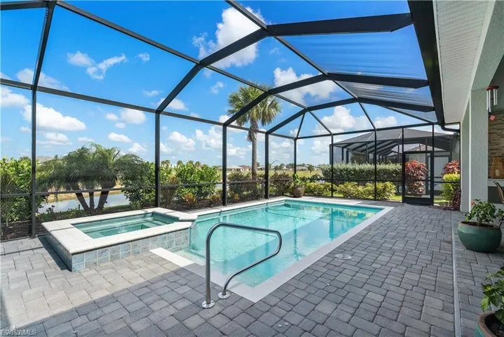 Screened lanai featuring a swimming pool, integrated spa, and paver decking