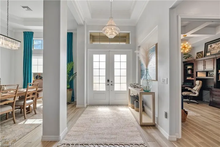 Double-door entry with transom window and elegant chandelier