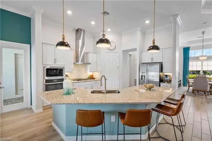 Gourmet kitchen featuring a large island with seating, stainless steel appliances, white cabinetry, and a honeycomb tile backsplash