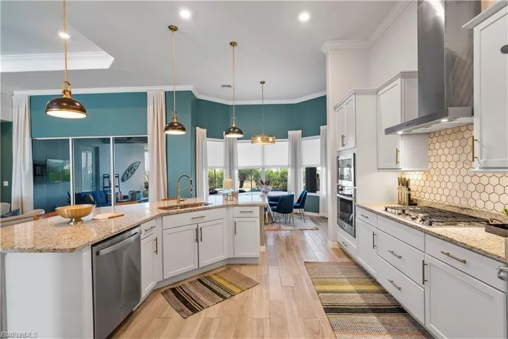 Gourmet kitchen with white cabinetry, stainless steel appliances, hexagon tile backsplash, and light-tone wood-finish flooring
