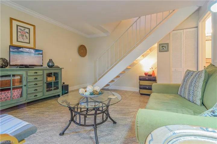 Living room, tastefully furnished with ceiling fan, crown moulding, and tile floors