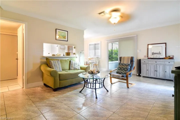 Living room, tastefully furnished with ceiling fan, crown moulding, and tile floors