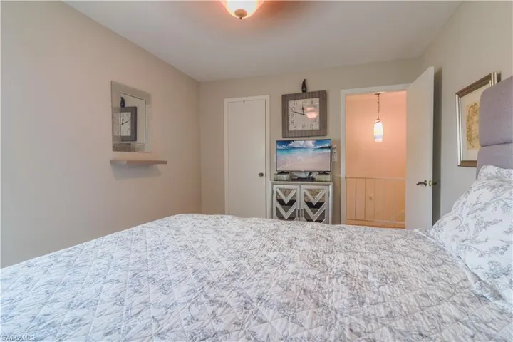 Primary bedroom with upholstered bed, warm wooden flooring, ceiling fan, and tasteful wall decor