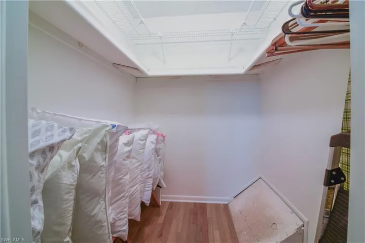 Spacious walk in closet in primary bedroom featuring warm hardwood flooring