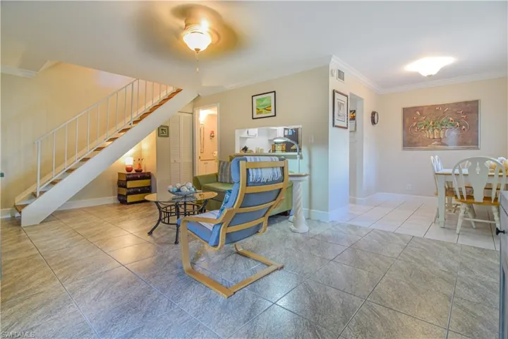 Living area with crown moulding, floating stairway, tile floors