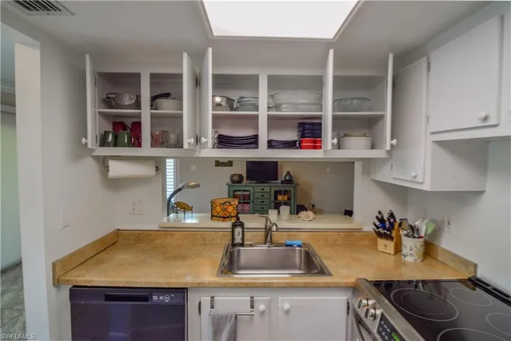 Kitchen featuring white cabinets, well stocked with dishware and cookware