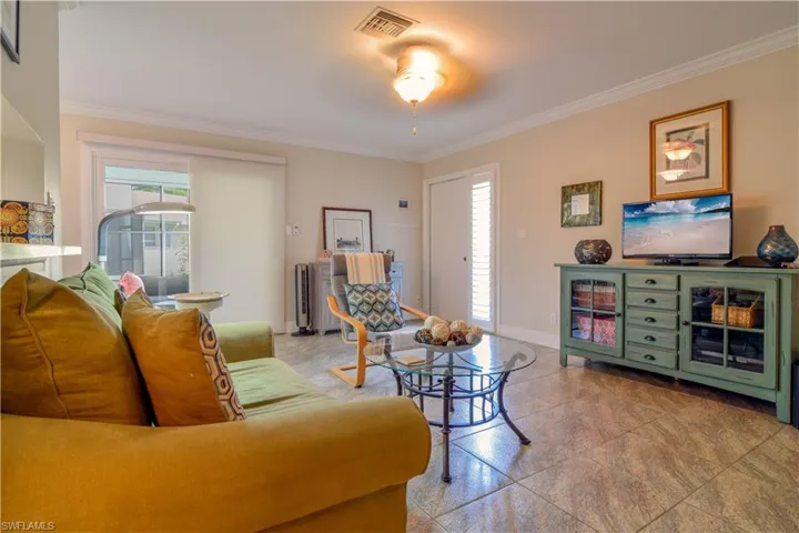 Living room, tastefully furnished with ceiling fan, crown moulding, and tile floors