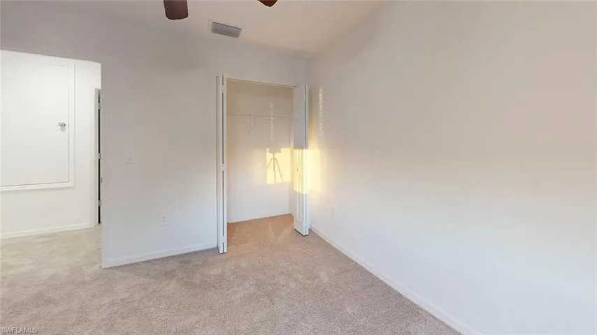 Neutral-toned carpeting, white painted walls, and a ceiling fan