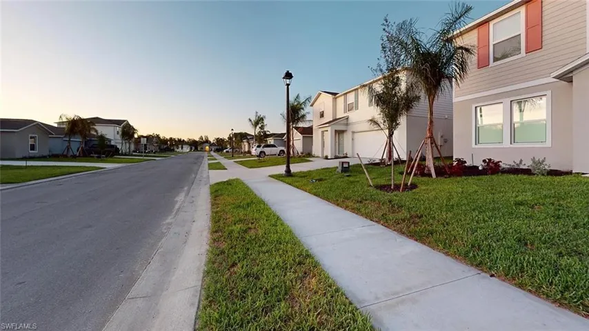 Suburban street with sidewalks, streetlights, and landscaped properties