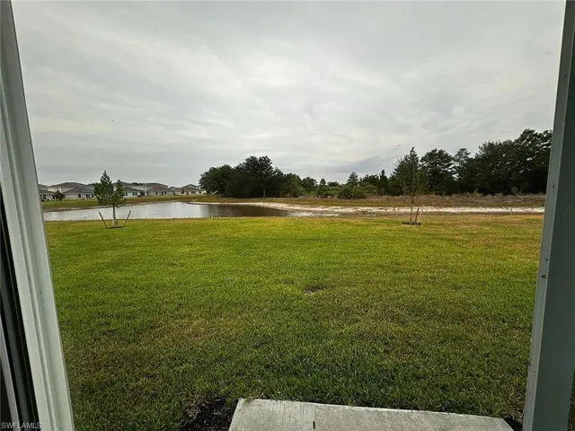 Expansive grassy area with a visible pond and mature trees