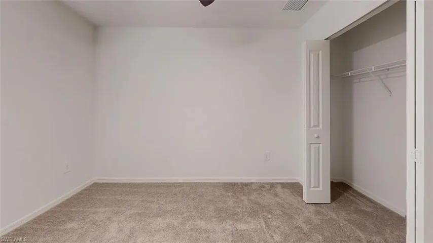 Plush carpet flooring, neutral wall tones, bi-fold closet doors, and wire shelving