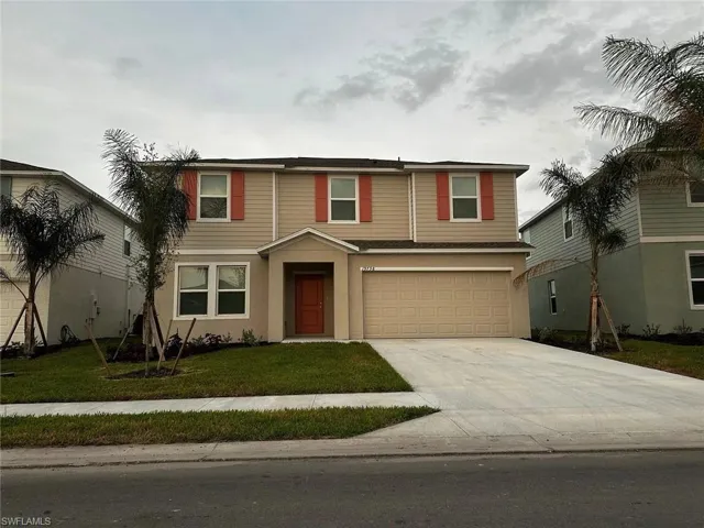Two-story residence featuring a covered entry, attached two-car garage, and established landscaping