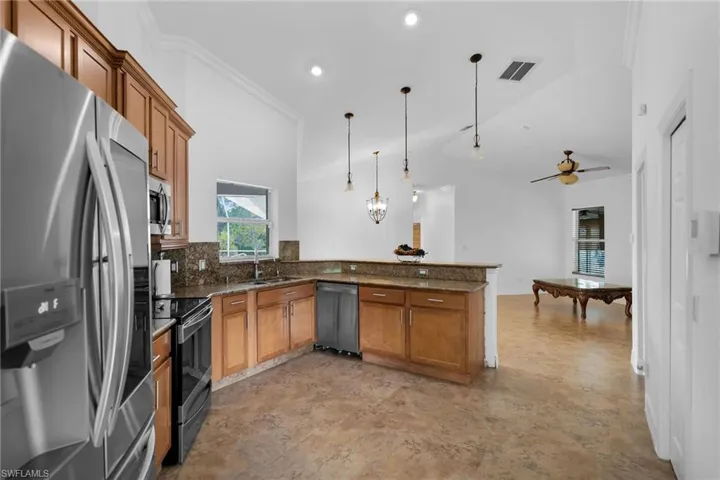 Kitchen featuring ceiling fan, pendant lighting, kitchen peninsula, stainless steel appliances, and pool table