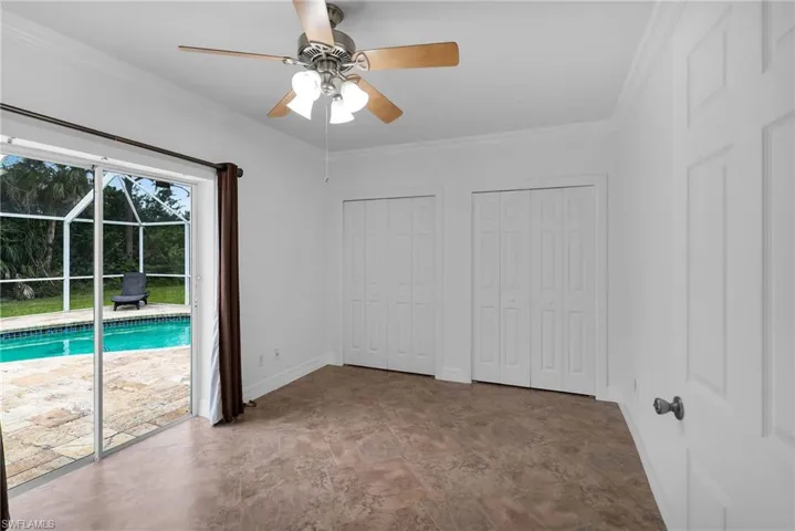 Unfurnished bedroom with ceiling fan, access to outside, crown molding, and multiple closets
