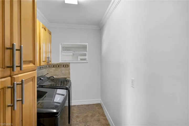Laundry area with independent washer and dryer, crown molding, and cabinets