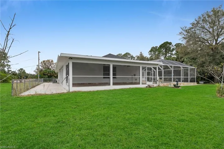 Rear view of house with a lawn, a patio area, and a lanai