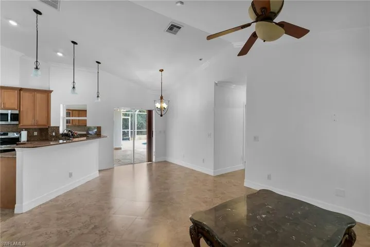 Kitchen with ceiling fan with notable chandelier, appliances with stainless steel finishes, lofted ceiling, hanging light fixtures, and crown molding