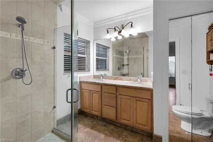 Bathroom featuring walk in shower, vanity, toilet, and crown molding