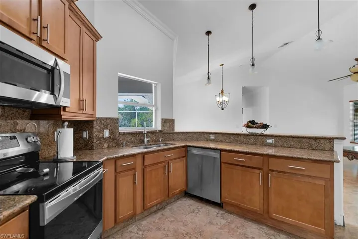 Kitchen with kitchen peninsula, stainless steel appliances, tasteful backsplash, pendant lighting, and sink