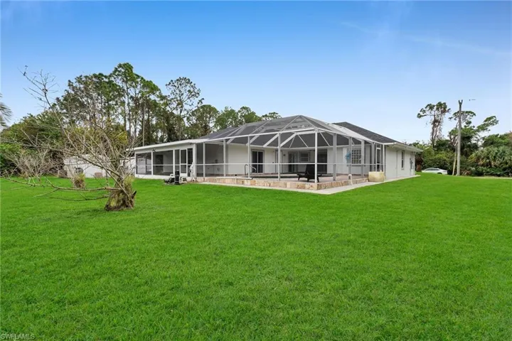 Back of house with a lanai and a yard