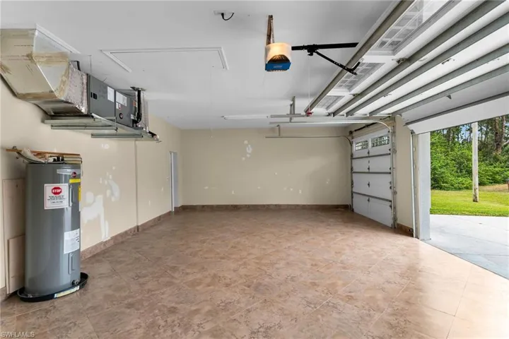 Garage featuring electric water heater and a garage door opener