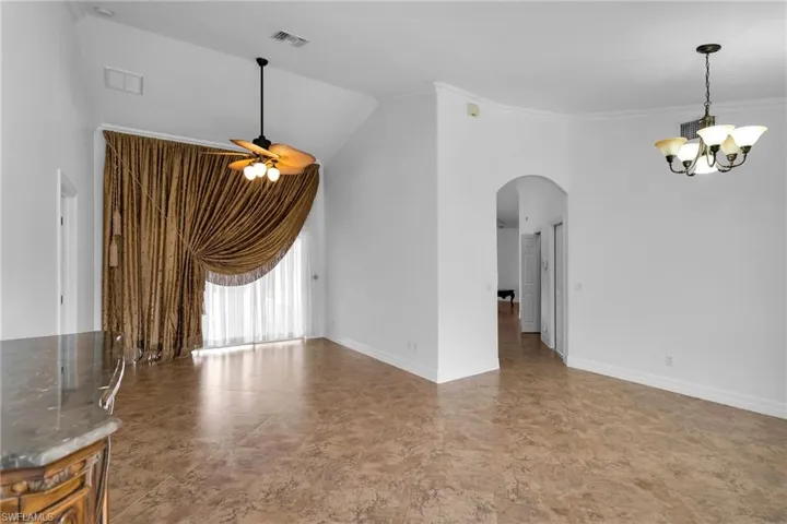 Empty room featuring ornamental molding and ceiling fan with notable chandelier