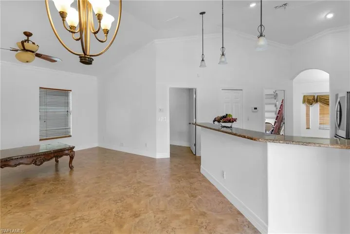 Kitchen featuring decorative light fixtures, stainless steel fridge, ceiling fan with notable chandelier, and crown molding