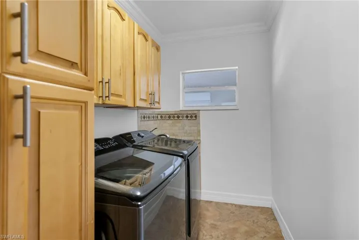 Clothes washing area featuring cabinets, ornamental molding, and independent washer and dryer