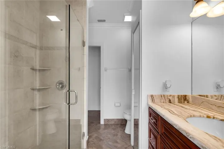 Bathroom with toilet, vanity, walk in shower, and ornamental molding