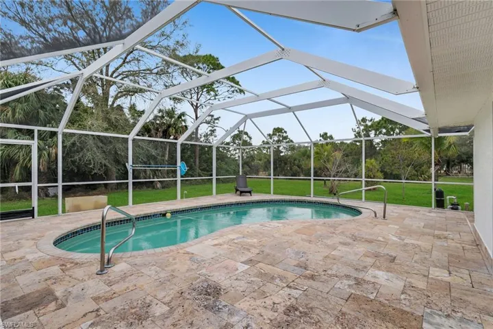 View of pool featuring glass enclosure, a lawn, and a patio