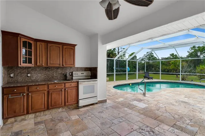 View of pool with exterior kitchen, a lanai, sink, and a patio area