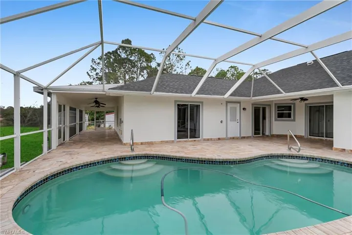 View of swimming pool featuring ceiling fan, a patio, and glass enclosure