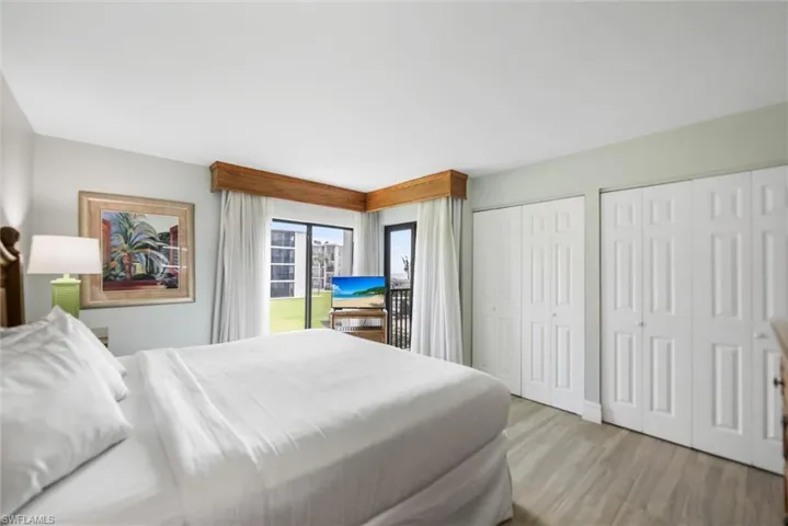 Bedroom with access to exterior, multiple closets, and wood finished floors