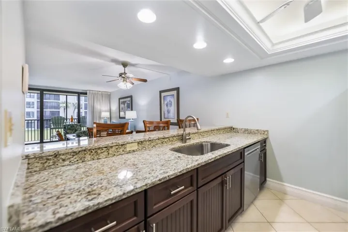 Kitchen featuring a ceiling fan, light stone countertops, dark brown cabinets, recessed lighting, and a peninsula