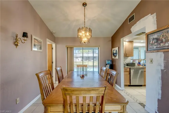 Tiled dining room with lofted ceiling and a chandelier