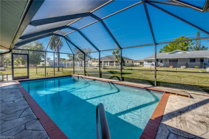 View of pool featuring a lawn and glass enclosure