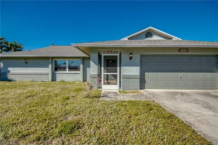 Ranch-style house featuring a garage and a front lawn