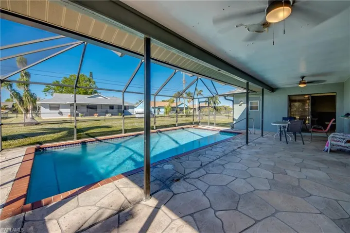 View of swimming pool featuring a patio area, ceiling fan, a lanai, and a lawn