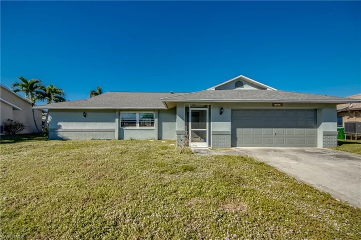 Ranch-style home featuring a garage and a front lawn