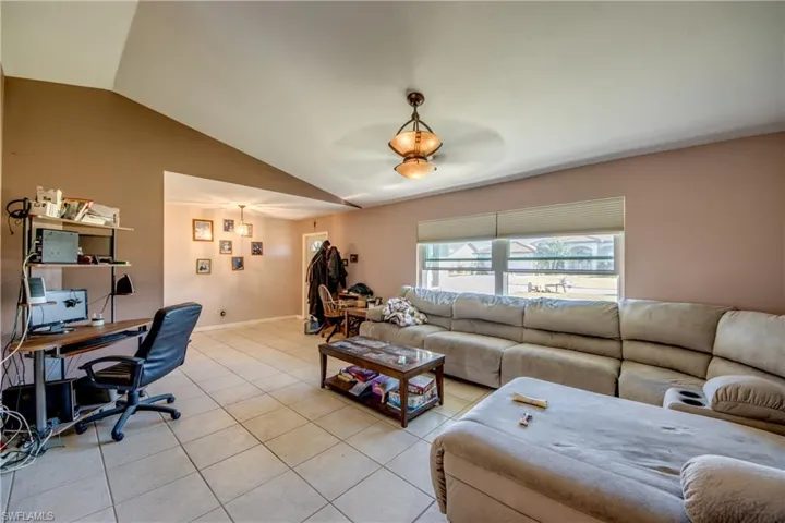 Tiled living room with ceiling fan and lofted ceiling