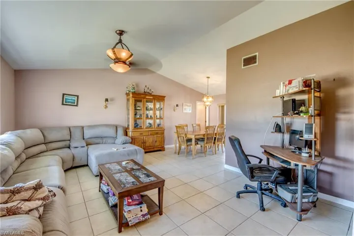 Tiled living room featuring vaulted ceiling and a notable chandelier