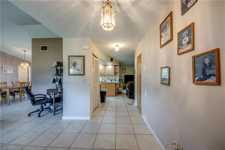 Hall featuring light tile patterned flooring and a chandelier