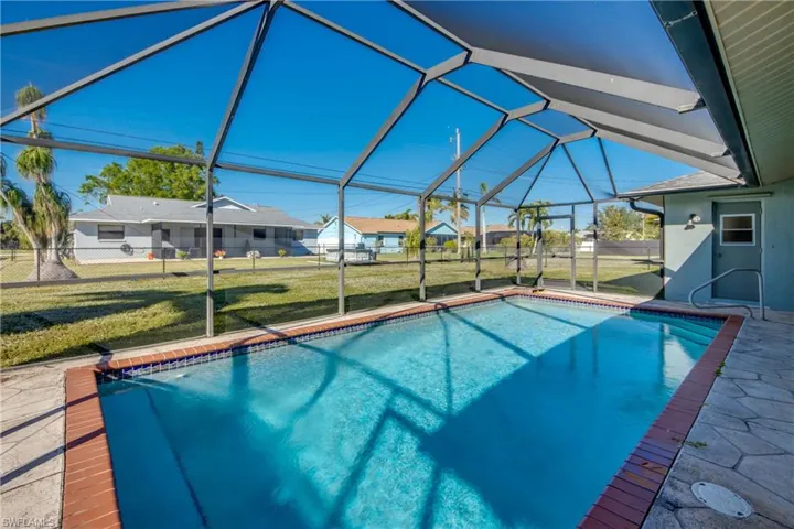View of pool with glass enclosure and a yard