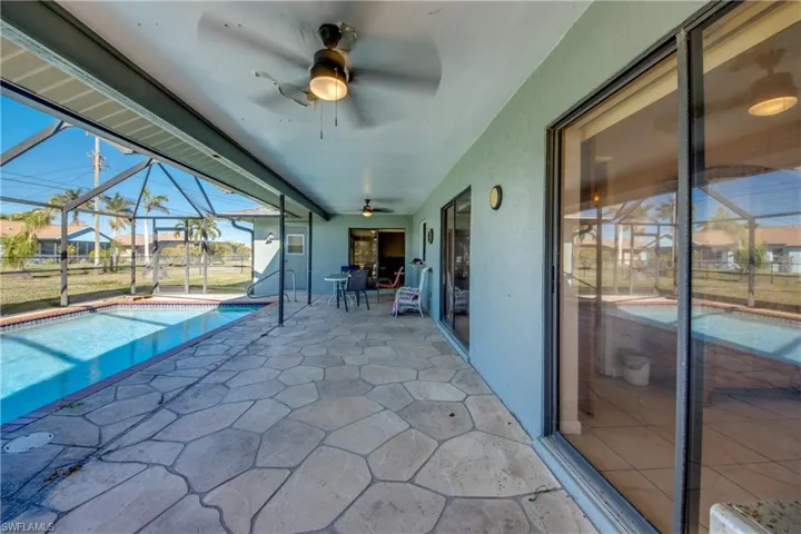View of swimming pool featuring a lanai, ceiling fan, and a patio