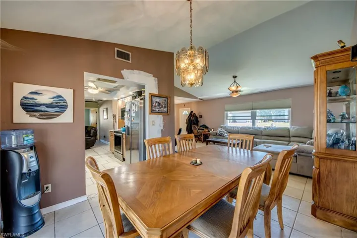 Dining room with light tile patterned flooring and ceiling fan with notable chandelier