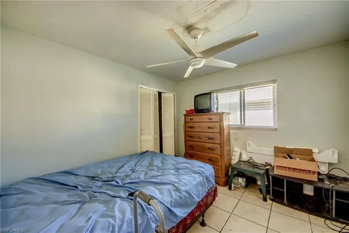 Tiled bedroom featuring ceiling fan and a closet