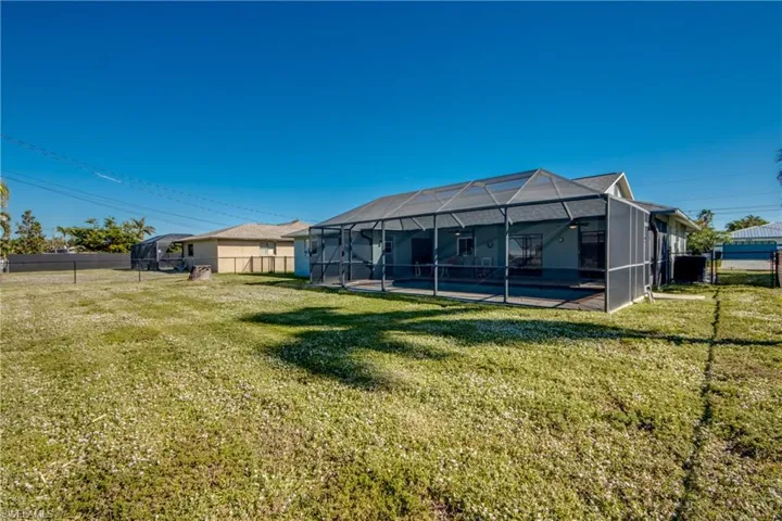 Back of house with a lawn, a lanai, and a pool